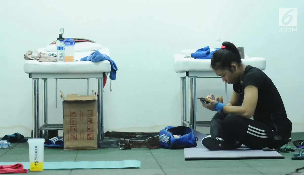 Salah satu lifter putri Indonesia melihat ponselnya disela-sela latihan tes prestasi pelatnas angkat besi Asian Games 2018 di Mako Lanmar Jakarta, Selasa (6/3). Tes ini mengukur kemajuan atlet jelang Asian Games 2018. (Liputan6.com/Helmi Fithriansyah)