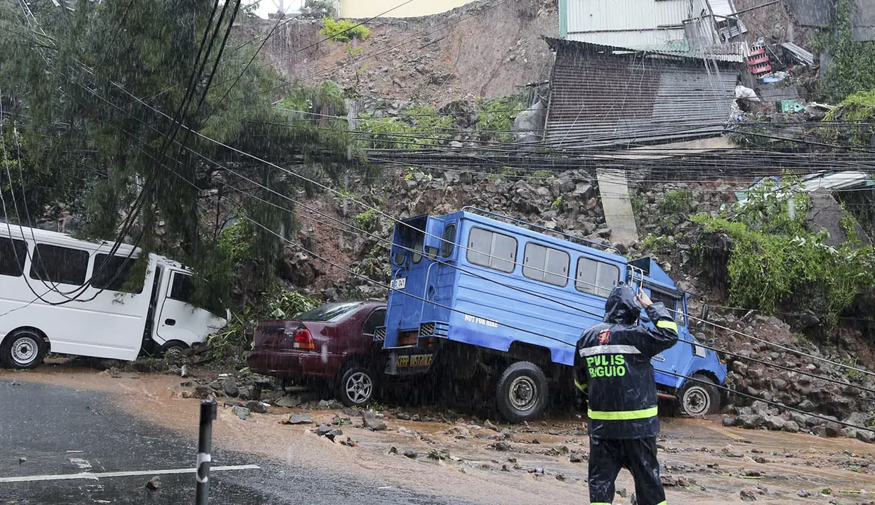 Seorang polisi memeriksa kendaraan yang terkena tanah longsor yang disebabkan oleh Topan Doksuri di Kota Baguio, Filipina utara pada hari Rabu 26 Juli 2023. (AP Photo)