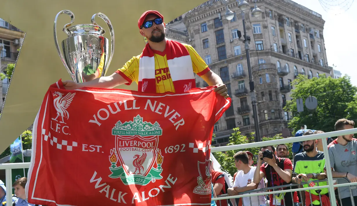 Fans Liverpool berpose dengan piala Liga Champions yang dipamerkan di Kiev, Ukraina , Kamis (24/5). Liverpool akan menghadapi Real Madrid di laga final Liga Champions. (Sergei SUPINSKY/AFP)