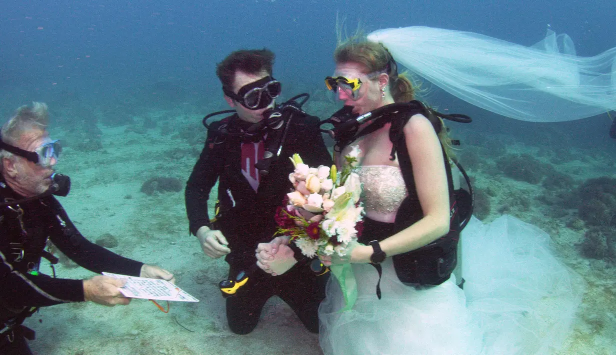 Pendeta John Hauk (kiri) membacakan sumpah pernikahan di bawah laut kepada pasangan Sersan Thomas Mould (tengah) dan Sandra Hyde dari Key Largo, Fla di Florida Keys National Marine Sanctuary (21/12). (Frazier Nivens/Florida Keys News Bureau via AP)