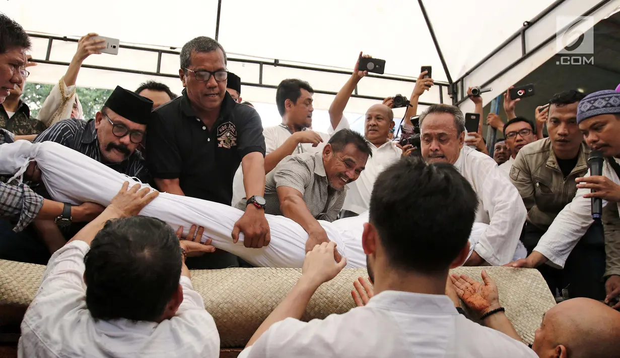 Sanak keluarga dan kerabat memasukkan jenazah artis senior RMH Heroe Siswanto atau dikenal Sys NS ke liang lahat di TPU Jeruk Purut, Jakarta, Selasa (23/1). (Liputan6.com/ Herman Zakharia)