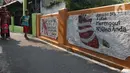 Warga melintasi mural bertema kawasan bebas asap rokok di lingkungan RW 06 Kelurahan Kayu Manis, Matraman, Jakarta, Jumat (8/10/2021). Beberapa titik pada kawasan tersebut juga terdapat mural-mural tentang pemberitahuan serta peringatan untuk tidak dan berhenti merokok (Liputan6.com/Herman Zakharia)