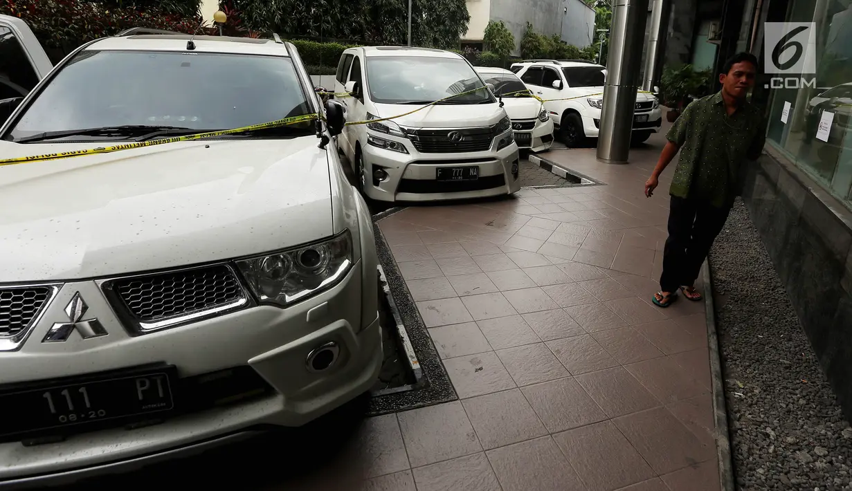 Seorang pria melewati deretan mobil mewah bos PT First Travel Andika Surachman dan Anniesa Hasibuan di Bareskrim Polri, Gedung KKP, Jakarta, Jumat (25/8). Mobil itu disita terkait kasus penggelapan dan penipuan jemaah umrah (Liputan6.com/Johan Tallo)