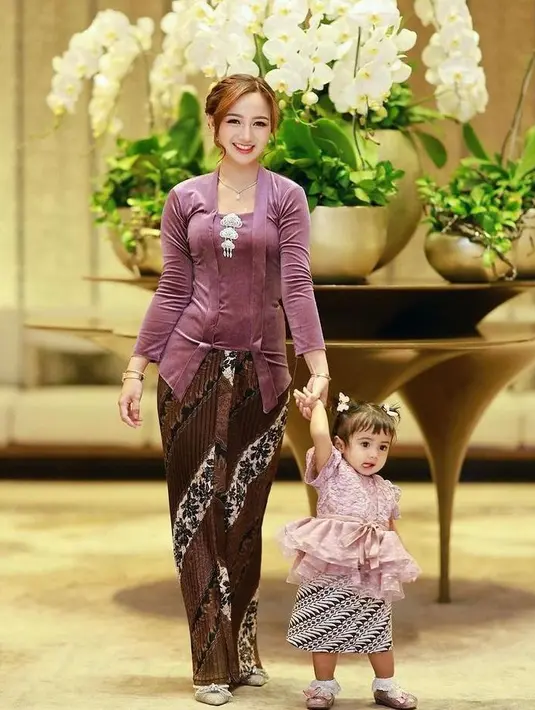 Selebgram dan beauty content creator Nanda Arsyinta mengenakan kebaya kutubaru bahan velvet warna ungu. Kebaya tersebut dipadukan kain batik coklat. [@nandaarsynt]