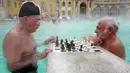Dua orang pria bermain catur sambil berendam di kolam relaksasi Szechenyi, di Budapest, Hongaria pada 13 Februari 2019. Szechenyi Thermal Bath adalah salah satu lokasi pemandian umum tertua dan terbesar di Budapest. (VALERY HACHE / AFP)