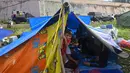 Seorang anak laki-laki mengintip dari tenda ketika orang-orang yang terkena gempa tinggal di kamp sementara setelah gempa berkekuatan 6,2 di Mamuju, Senin (18/1/2021). Ratusan jiwa telah mengungsi di sejumlah posko pengungsian karena rumah mereka rusak akibat gempa. (AFP/Adek Berry)