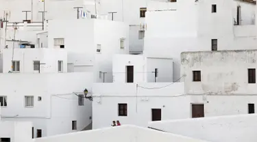 Pasangan berjalan di antara bangunan serba putih di Pueblos Blancos, Andalusia, Spanyol, 16 September 2016. Pueblos Blancos atau Desa Putih merupakan kota yang terdiri dari sekumpulan desa dengan seluruh bangunan bercat putih. (REUTERS/Marcelo del Pozo)