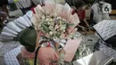 Perajin menata buket atau karangan bunga di Pasar Bunga Rawa Belong, Jakarta, Senin (14/2/2022). Perajin buket setempat mengaku permintaan pesanan karangan bunga yang biasa dihadiahkan saat hari kasih sayang atau Valentine Day tersebut menurun. (Liputan6.com/Faizal Fanani)