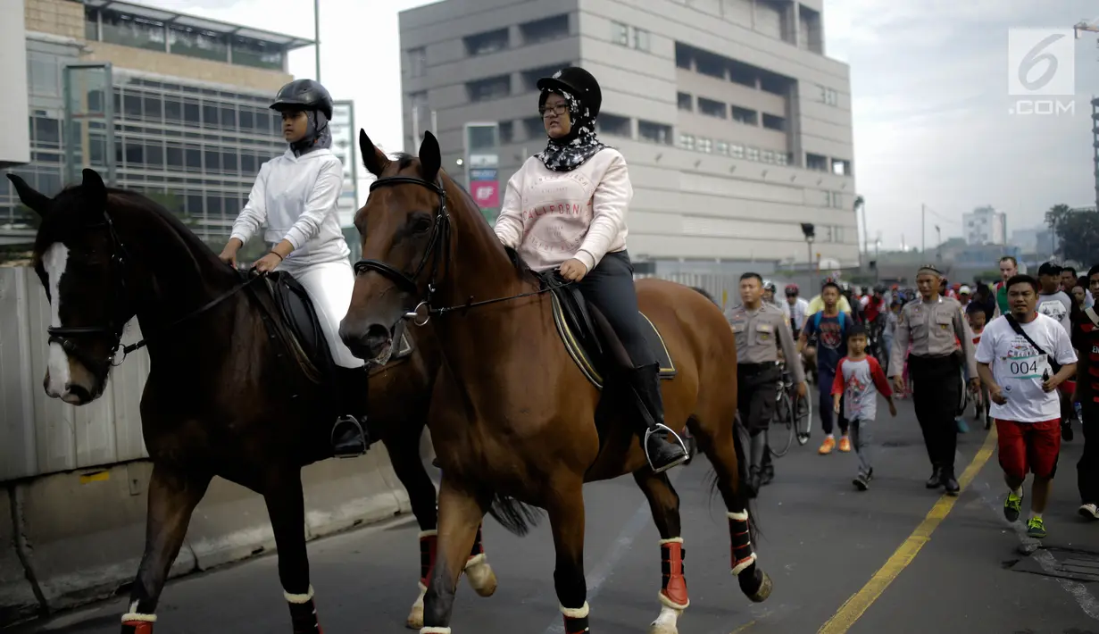 Dua pengunjung berkeliling area car free day  dengan menunggang kuda milik satuan polisi berkuda Polda Metro Jaya di Bundaran HI, Jakarta, Minggu (18/3). Kuda-kuda yang diterjunkan itu menarik perhatian pengunjung. (Liputan6.com/Faizal Fanani)