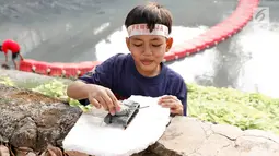 Seorang anak bermain di pinggir sungai buatan di kawasan Kuningan, Jakarta, Senin (13/8). Meskipun tidak baik bagi kesehatan dan keselamatan mereka, anak-anak tersebut tempat bermain di sungai tersebut. (Liputan6.com/Immanuel Antonius)