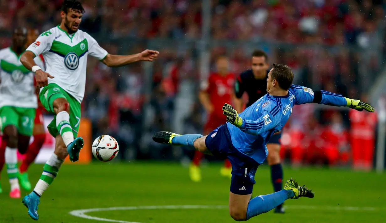 Kiper Muenchen, Manuel Neuer (kiri) berusaha mengamankan bola dari kejaran Gelandang Wolfsburg, Daniel Caligiuri pada bundesliga di Allianz Arena, Rabu (23/9/2015). Muenchen menang telak atas Wolfsburg dengan skor 5-1. (AFP PHOTO/Michael Dalder)