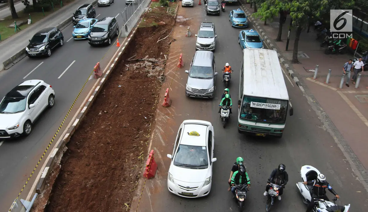 Sejumlah kendaraan melintas di samping penataan jalan dan trotoar di Jalan Sudirman, Jakarta, Selasa (17/4). Trotoar tersebut akan dilebarkan menjadi 9 hingga 12 meter. (Liputan6.com/Arya Manggala)