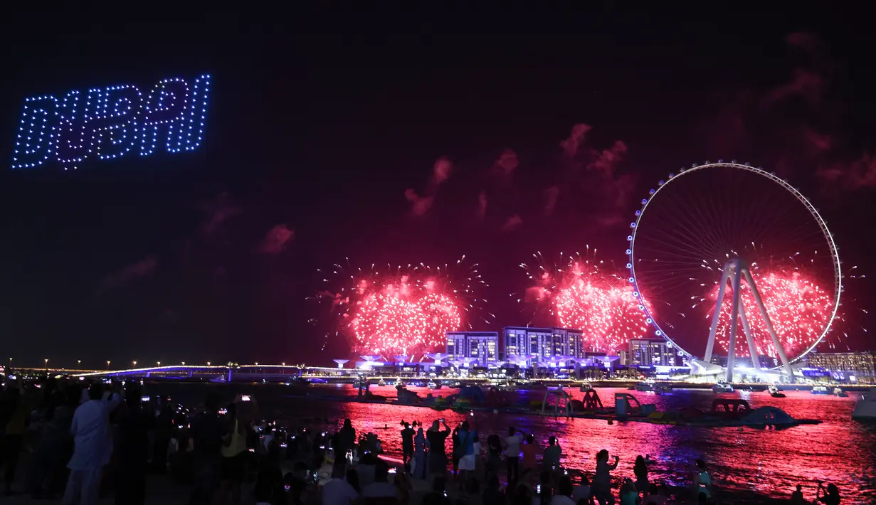Kembang api menerangi langit selama upacara pembukaan Dubai Eye, yang dikenal sebagai Ain Dubai, di kota Emirat, dekat Dubai Marina, Kamis (21/10/2021). Pembukaan bianglala terbesar di dunia ini dilakukan dengan pesta kembang api serta pertunjukan drone. (Giuseppe CACACE / AFP)