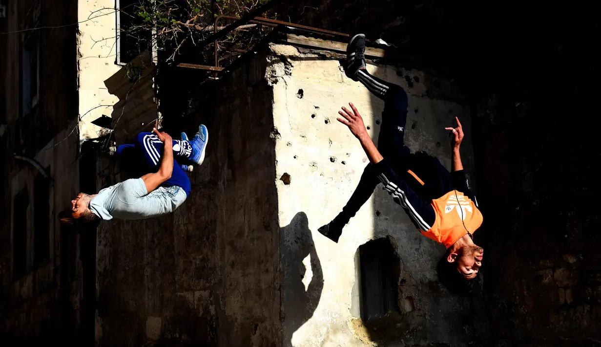 Dua pemuda melompat berlatih parkour di Aleppo, Suriah, (7/4). Para pemuda memanfaatkan reruntuhan bangunan akibat perang menjadi tempat untuk melatih kelincahannya bermain Parkour. (AFP Photo/George Ourfalian)