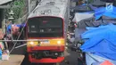 Kereta commuter line melintas di rel KRL Nambo yang dipadati aktivitas jual beli pasar dadakan, Citeureup, Bogor (20/4). Pasar dadakan ini digelar setiap hari Jumat. (Merdeka.com/Arie Basuki)