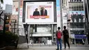 Pejalan kaki melihat layar yang menampilkan pertemuan antara pemimpin Korea Utara Kim Jong-un dan Presiden AS Donald Trump di Tokyo, Selasa (12/6). Untuk pertama kalinya dalam sejarah, Donald Trump dan Kim Jong-un bertemu. (AFP PHOTO/Martin BUREAU)