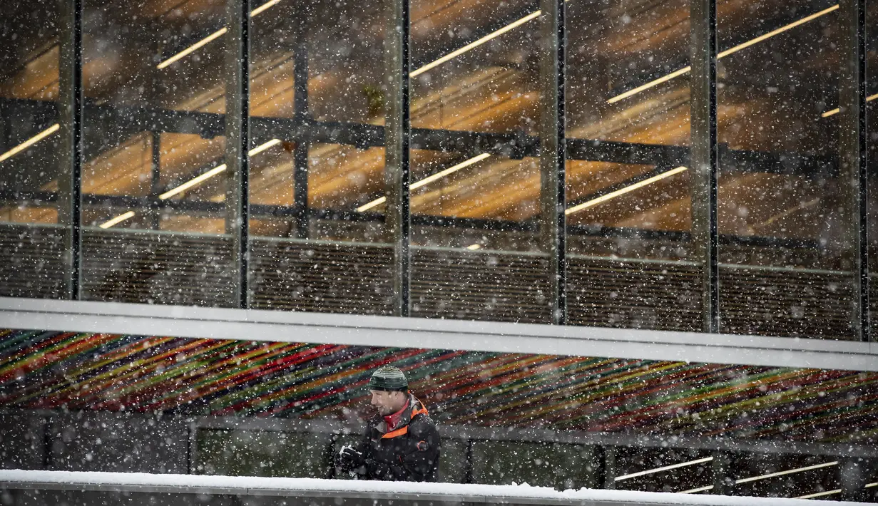 Seorang pria membentuk bola salju saaat hujan salju lebat turun saat di Universitas Simon Fraser, Burnaby, British Columbia, Kanada (21/12/2020). Hujan salju lebat juga melanda Taman Kensington Vancouver. (Darryl Dyck/The Canadian Press via AP)