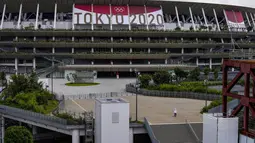 Seorang pekerja berjalan melalui pintu depan Stadion Nasional, satu bulan sebelum pembukaan Olimpiade Tokyo, di Tokyo, Rabu (23/6/2021). Olimpiade Tokyo dimulai pada 23 Juli dan penyelenggara mengizinkan penonton lokal menghadiri venue pertandingan dengan kapasitas 50 persen (AP Photo/Kiichiro Sato)