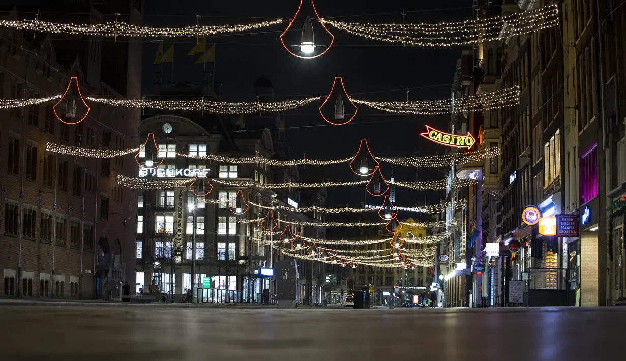 Jalan Damrak yang sepi terlihat selama jam malam di jantung kota Amsterdam, Sabtu (23/1/2021). Belanda memasuki fase terberat dari pembatasan anti-virus Corona hingga saat ini. (AP Photo/ Peter Dejong)