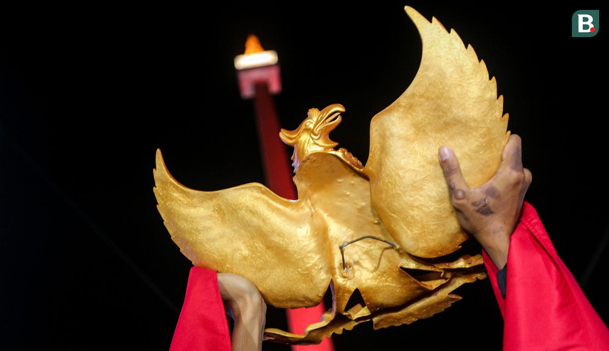 Seorang suporter Timnas Indonesia U-23 mengangkat patung Garuda Pancasila saat nonton bareng pertandingan perebutan juara ketiga Piala Asia U-23 2024 antara Timnas Indonesia U-23 melawan Irak U-23 di Kompleks Monumen Nasional (Monas), Jakarta, Kamis (03/05/2024). (Bola.com/Bagaskara Lazuardi)