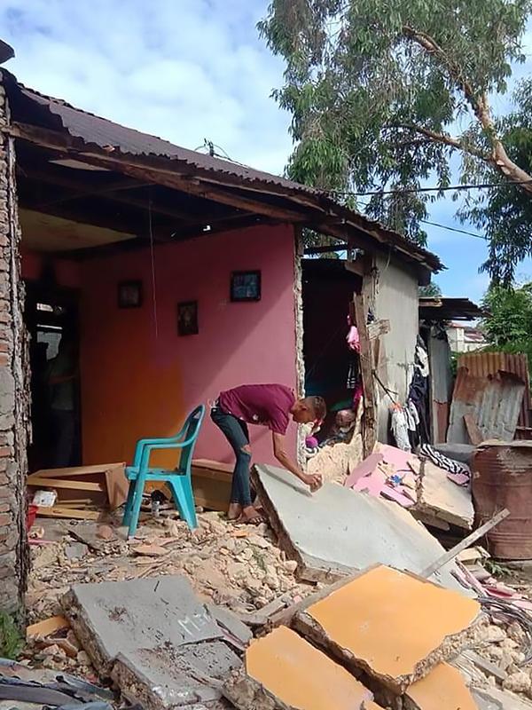 Seorang warga memeriksa tembok rumahnya yang ambruk setelah gempa berkekuatan 6,8 di Ambon, kepulauan Maluku (26/9/2019). Gempa bumi magnitudo 6,8 guncang kawasan timur Indonesia tepatnya di Ambon Maluku Kamis (26/9/2019) pagi. (AFP Photo/Aisyah Putri)