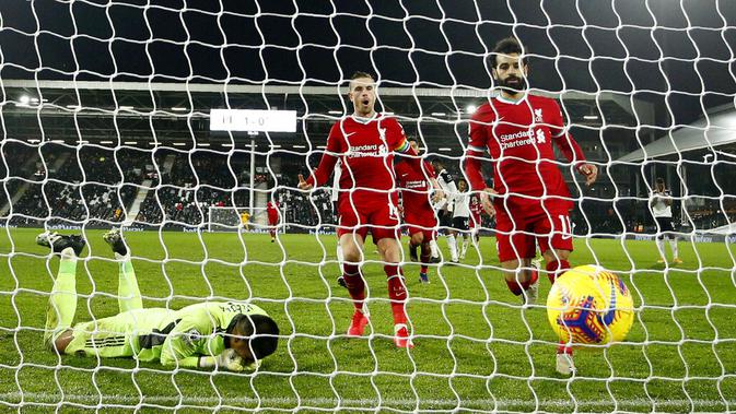 Pemain Liverpool Mohamed Salah (kanan) berlari untuk mengambil bola usai mencetak gol dari titik penalti ke gawang Fulham pada pertandingan Liga Premier Inggris di Stadion Craven Cottage, London, Minggu (13/12/2020). Liverpool dan Fulham bermain imbang 1-1. (AP photo/Matt Dunham, Pool)