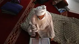 Seorang pria Muslim yang mengenakan masker wajah membaca Alquran di Masjid Agung Faisal pada awal Itikaf, di sebuah masjid untuk pria selama bulan suci Ramadhan di Islamabad (3/5/2021). (AFP/Aamir Qureshi)