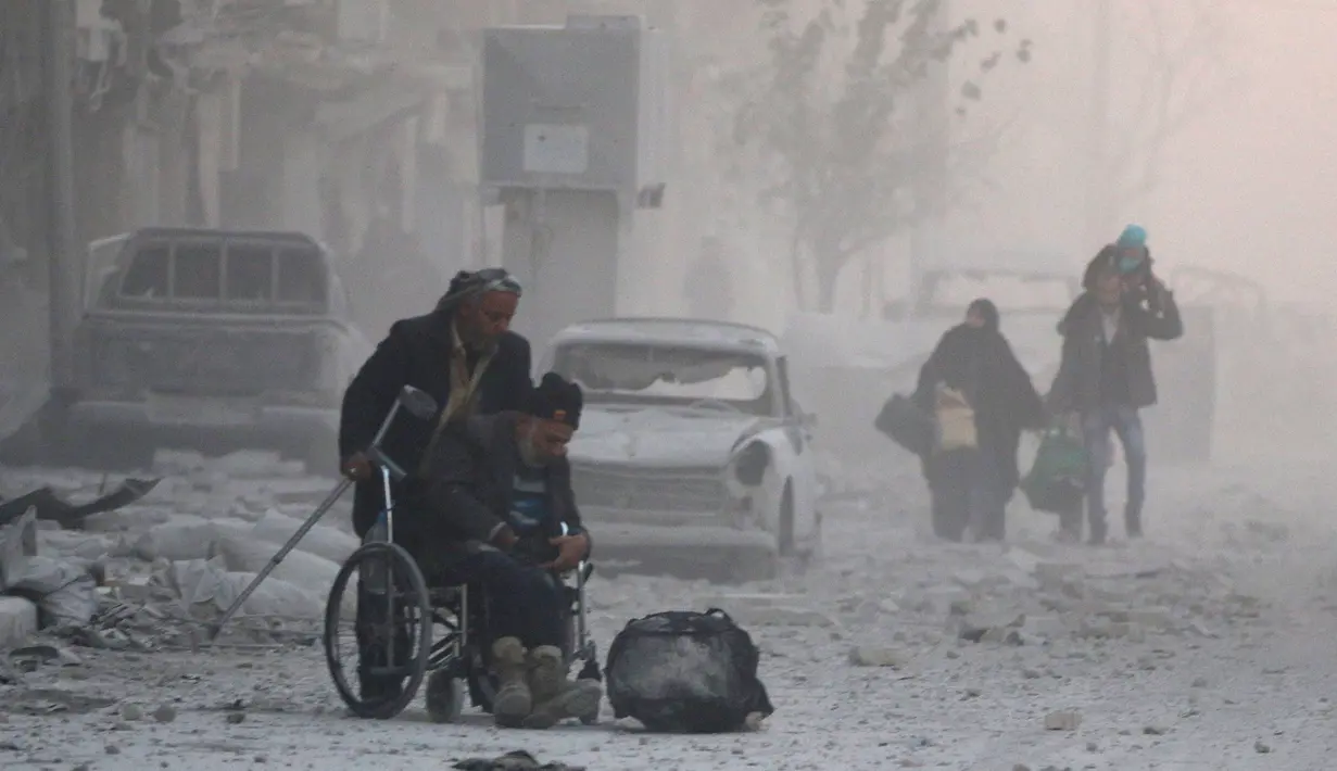 Seorang pria di kursi roda melarikan diri dengan sejumlah warga yang lain dari wilayah yang dikuasai pemberontak, Aleppo, Suriah (9/12). (REUTERS / Abdalrhman Ismail)
