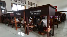 Sejumlah siswa SD berlindung di bawah meja selama latihan tsunami di Tanjung Benoa dekat Denpasar di pulau resor Bali (15/8). (AFP Photo/ Sonny Tumbelaka)