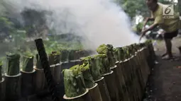 Pak Pian memeriksa kayu bakar saat memasak lemang bambu sebuah tanah kosong di Jakarta, Minggu (27/5). Pak Pian mengaku dapat memproduksi hingga 100 buah lemang per hari di bulan Ramadan. (Merdeka.com/Iqbal S Nugroho)