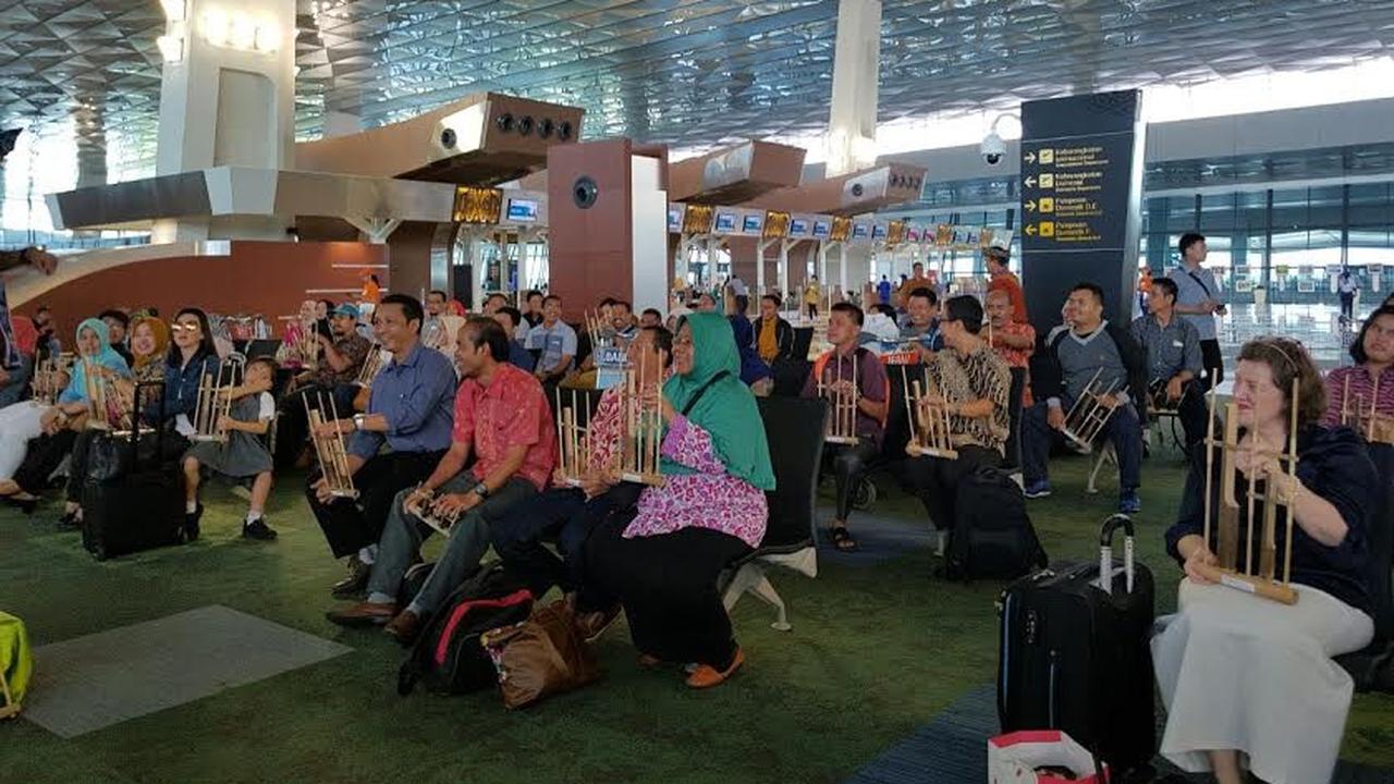 penumpang pesawat di terminal 3 Bandara Soekarno Hatta memainkan angklung dengan dipandu seorang instruktur (Liputan6.com/Pramita Tristiawati)
