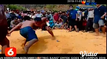 Peserta gulat tradisional Madura (Okol) berusaha saling membanting saat pertandingan, di Desa Akor, Pamekasan, Jawa Timur, Jumat (1/11/2019). Tradisi yang digelar tiap akhir musim kemarau itu sebagai permohonan kepada Tuhan agar turun hujan.