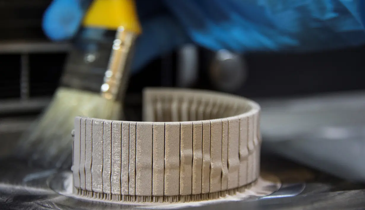 Seorang pekerja Comite Franceclat membersihkan bubuk emas ketika proses pembuatan gelang emas 'Dunes' dengan mesin cetak 3D di laboratorium penelitian 'Franceclat', Besancon, Prancis timur, 11 Oktober 2017. (AFP FOTO / SEBASTIEN BOZON)