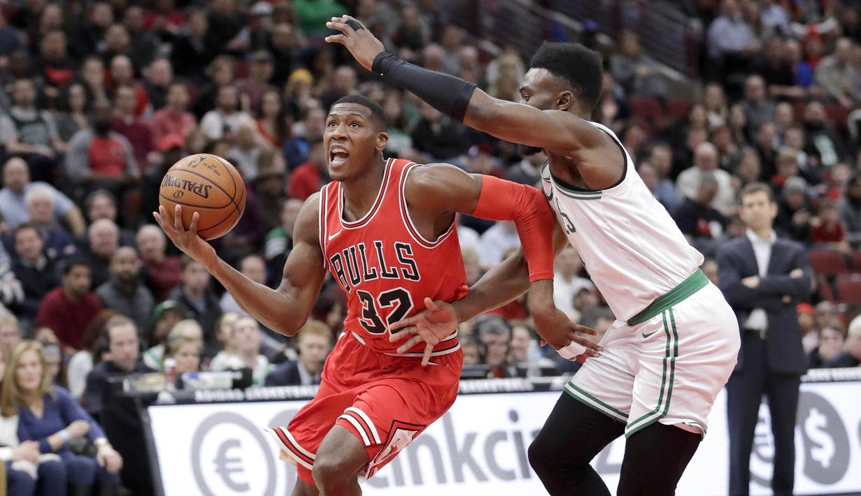 Pebasket Chicago Bulls, Kris Dunn, berusaha melewati pebasket Boston Celtics, Jaylen Brown, pada laga NBA di Stadion United Center, Selasa (6/3/2018). Celtics menang 105-89 atas Bulls. (AP/Charles Rex Arbogast)