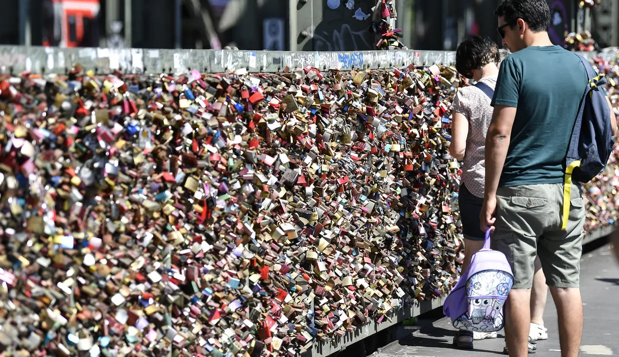 Warga melewati gembok cinta di sebuah jembatan di Cologne, Jerman, Rabu, (5/8/2020). Sebagai bukti cinta mereka, puluhan ribu pasangan telah memasang gembok selama bertahun-tahun ke pagar di Jembatan Hohenzollern sebelum melemparkan kunci ke dalam Sungai Rhein di bawah. (AP Photo/ Martin Meissner)