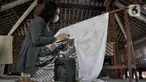 Rita saat menyelesaikan pembuatan batik tulis Lumbini di Dusun Tingal, Desa Wanurejo, Kecamatan Borobudur, Kabupaten Magelang, Jawa Tengah, Selasa (17/5/2022). Pasangan suami istri Adiwinarto (56) dan Rita (53) merintis batik tulis Lumbini pada 2011. (merdeka.com/Iqbal S. Nugroho)