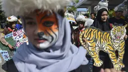 Sejumlah pelajar membawa gambar harimau saat melakukan aksi demonstrasi dalam peringatan Hari Bumi Sedunia di Banda Aceh (22/4). Mereka menyerukan penyelamatan empat satwa kunci yang terancam punah. (AFP Photo/Chaideer Mahyuddin)