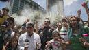Seorang reporter ikut terkena semprotan busa saat fans Meksiko merayakan kemenangan timnya atas Jerman di Monumen Angel of Independence,  Meksiko City (17/6/2018). Meksiko menang 1-0. (AP/Anthony Vazquez)