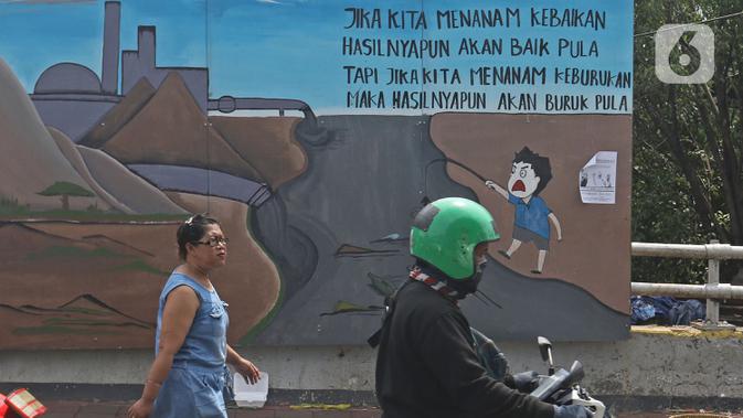 Pejalan kaki dan warga melintasi mural yang berisi pesan ajakan untuk menjaga lingkungan di Jalan Tambak, Manggarai, Jakarta, Selasa (11/2/2020). Mural tersebut bertujuan mengingatkan bahwa permasalahan lingkungan merupakan masalah serius yang harus dihadapi bersama. (Liputan6.com/Herman Zakharia)