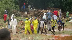 Petugas penyelamat membawa mayat korban dari lokasi tanah longsor di Regent, sebelah timur Freetown, Sierra Leone, (14/8). Bencana ini terjadi saat penduduk tengah tidur sehingga banyak yang terjebak di dalam rumah. (AP Photo / Manika Kamara)