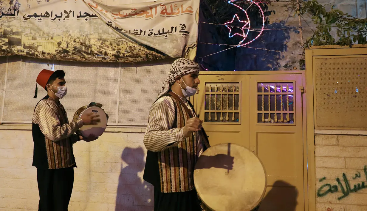 Pria Palestina yang dikenal dengan "Musaharatis" saat bertugas sebagai "penabuh drum Ramadhan" di kota tua Hebron, Tepi Barat pada 14 April 2021. Membangunkan sahur sudah menjadi tradisi yang sudah mereka lakukan selama Ramadhan. (HAZEM BADER/AFP)