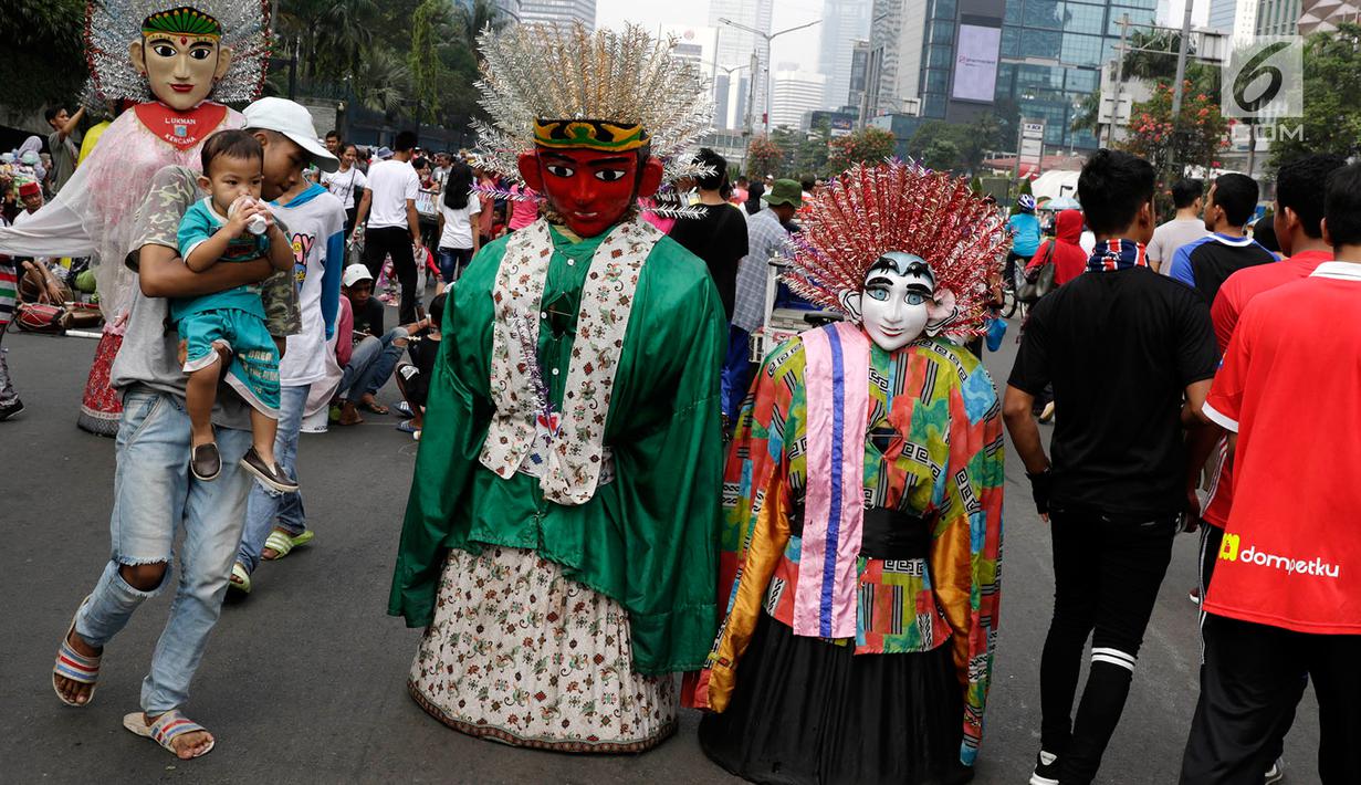Pengamen ondel-ondel meminta sumbangan kepada warga di lokasi car free day, Jakarta, Minggu (21/5). Ramainya pengunjung CFD menyebabkan banyak pengamen mencari rezeki di kegiatan yang berlangsung setiap minggu tersebut. (Liputan6.com/Immanuel Antonius)