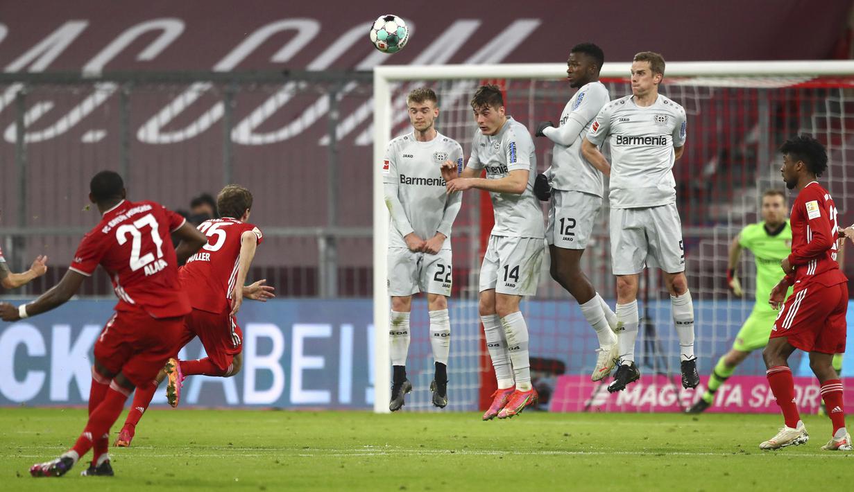 Bek Bayern Munich, David Alaba (kiri) melepaskan tendangan bebas ke gawang Bayer Leverkusen dalam laga lanjutan Liga Jerman 2020/2021 pekan ke-30 di Allianz Arena, Munich, Selasa (20/4/2021). Bayern Munich menang 2-0 atas Leverkusen. (AP/Matthias Schrader/Pool)