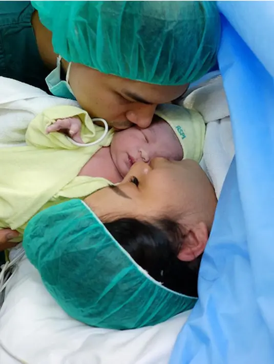 Sang suami Glenn mengunggah foto saat mencium buah hatinya setelah sekitar sejam istrinya melahirkan. Dalam foto, keduanya terlihat sedang mencium buah hatinya. (dok. Instagram/glennalinskie)
