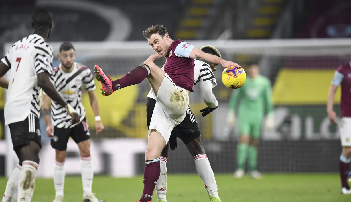 Bek Burnley, Ben Mee mencoba menghentikan gelandang Manchester United, Paul Pogba dalam partai tunda Liga Inggris 2020/21 di Turf Moor, Rabu (13/1/2021) dini hari WIB. Manchester United sukses mengalahkan Burnley dengan skor tipis 1-0. (Peter Powell/Pool via AP)
