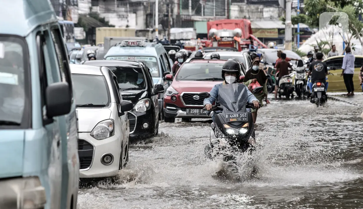 Sejumlah kendaraan terjebak kemacetan akibat banjir yang menggenangi Jalan Jatinegara Barat, Jakarta, Senin (8/2/2021). Banjir yang menggenangi Jalan Jatinegara Barat terjadi akibat luapan Kali Ciliwung yang dipicu hujan deras di Jakarta dan Bogor sejak dini hari tadi. (merdeka.com/Iqbal S. Nugroho)