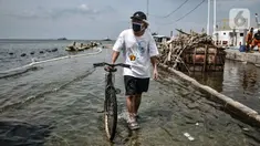 Warga menuntun sepeda saat melintasi banjir rob di Pelabuhan Kali Adem, Muara Angke, Jakarta, Kamis (22/10/2020). Banjir akibat air pasang dengan ketinggian mencapai 30 cm tersebut telah merendam kawasan Pelabuhan Kali Adem dan sudah berlangsung selama lima hari. (merdeka.com/Iqbal S. Nugroho)