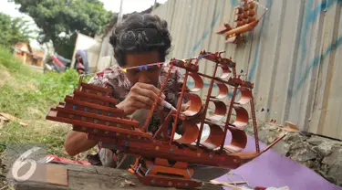 Perajin merekatkan miniatur perahu phinisi yang terbuat dari bambu, Jawa Barat, Sabtu (9/7). Perajin mengaku membanjirnya produk kerajinan dari China menyebabkan terhentinya ekspor dan penurunan permintaan dalam negeri. (Liputan6.com/Gempur M Surya)