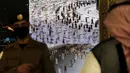 Petugas keamanan Arab Saudi menonton layar pintar yang mengidentifikasi otorisasi peziarah yang lewat untuk berpartisipasi dalam ibadah haji jelang pelaksanaan ibadah haji di pusat penerimaan jemaah al Zaidy, Mekah, Arab Saudi, Senin (12/7/2021). (AP Photo/Amr Nabil)