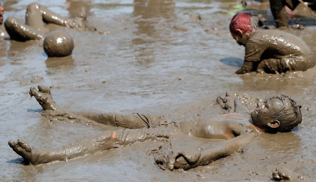 Nathan Jamerson, 10, bermain dalam kubangan lumpur saat Mud Day atau Hari Lumpur di Michigan, negara bagian AS, Selasa (9/7/2019). Para peserta perayaan yang menjadi tradisi setiap tahun ini merupakan anak-anak untuk agar mereka bersenang-senang selama liburan musim panas.  (AP/Carlos Osorio)